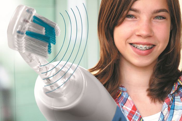 girl with braces holding Emmi-Dent Ultrasound toothbrush