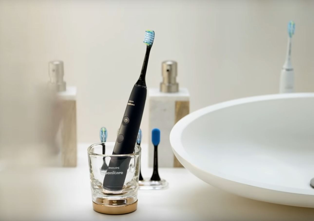 black philips sonicare diamondclean smart toothbrush in charging glass on bathroom counter